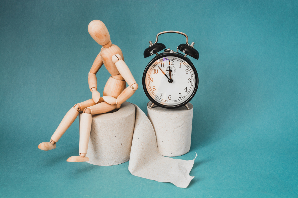 wooden figure seated on a toilet paper role with clock