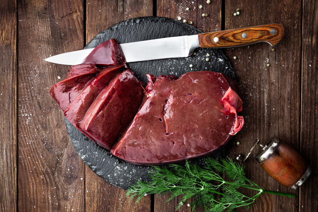 raw liver on serving stone with knife salt and dill