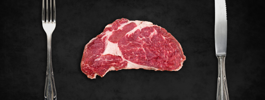 rib eye steak raw with fork and knife
