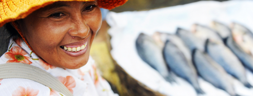 healthy indegenous woman smiling with fish in the background