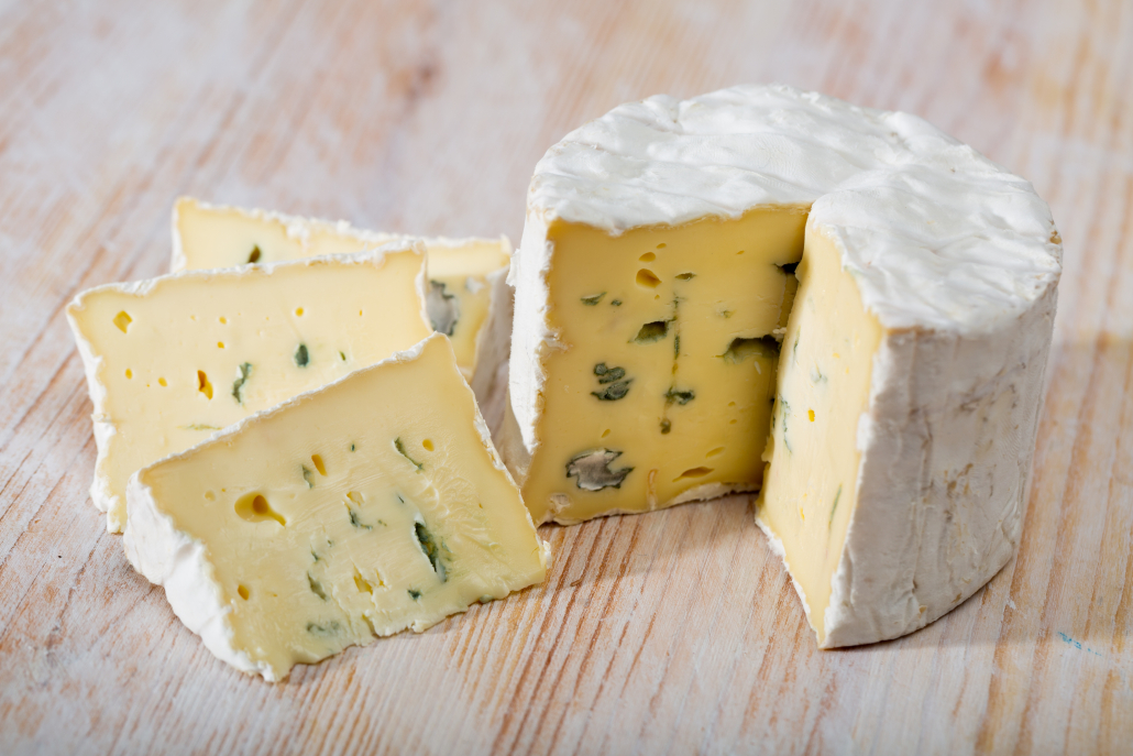 View of pieces of piquant creamy blue cheese on wooden board