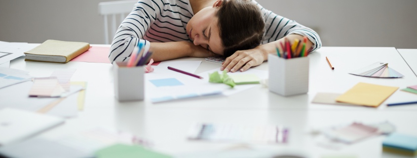 Portrait of contemporary young woman sleeping on table at work , copy space