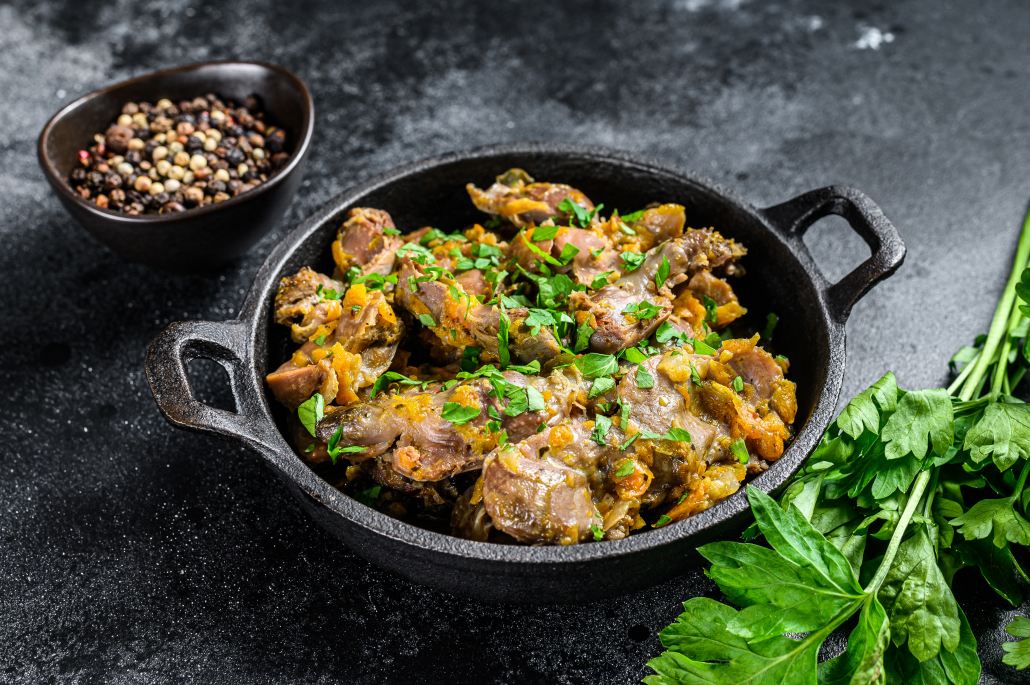 Chicken liver, heart and stomach in cream sauce. Black background. Top view.