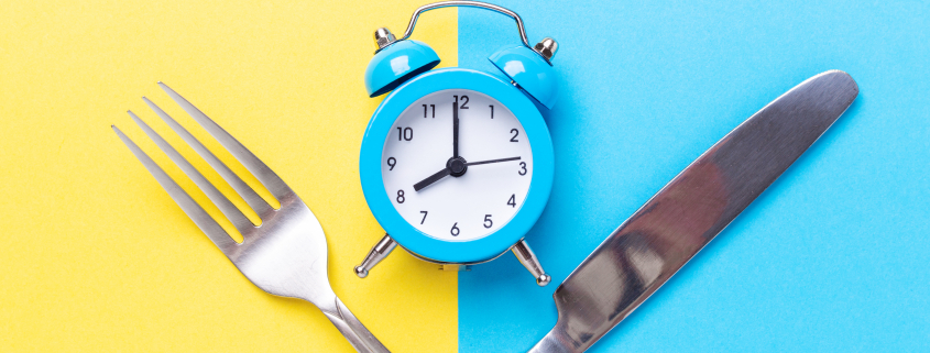 Blue alarm clock, fork, knife on colored paper background. Intermittent fasting concept - Image