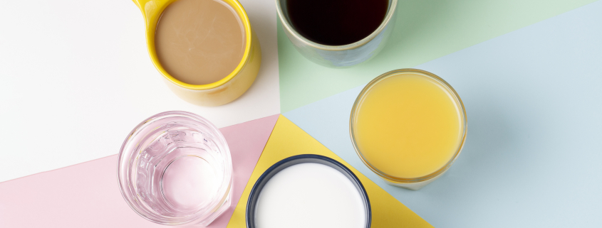 Coffee tea and other drinks in colorful cups on a multicolored background, top view