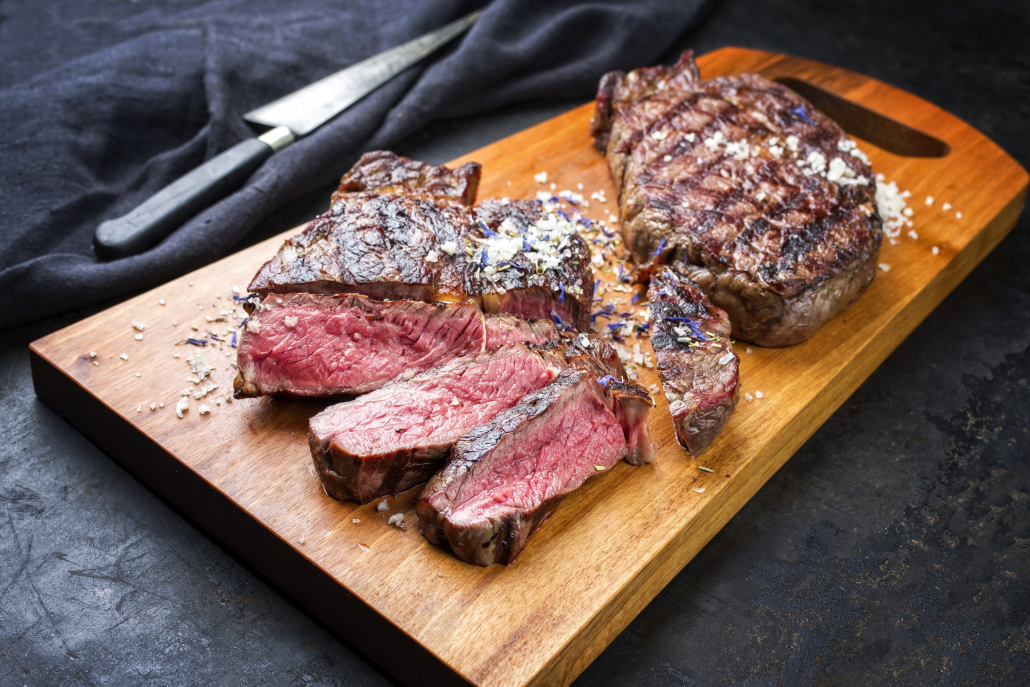 Traditional barbecue dry aged wagyu entrecote beef steak sliced with salt and spice as closeup on modern design wooden cutting board