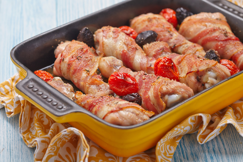 Bacon wrapped chicken legs with tomato and olives