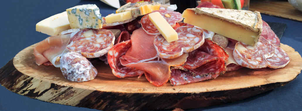 Chunks of gourmet cow and goat cheese, liver pate, sliced cured meats, fatty sausages and salami served on a piece of wood