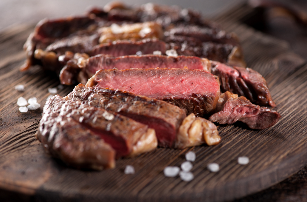 Sliced medium rare grilled beef steak ribeye close-up on a brown rusty background