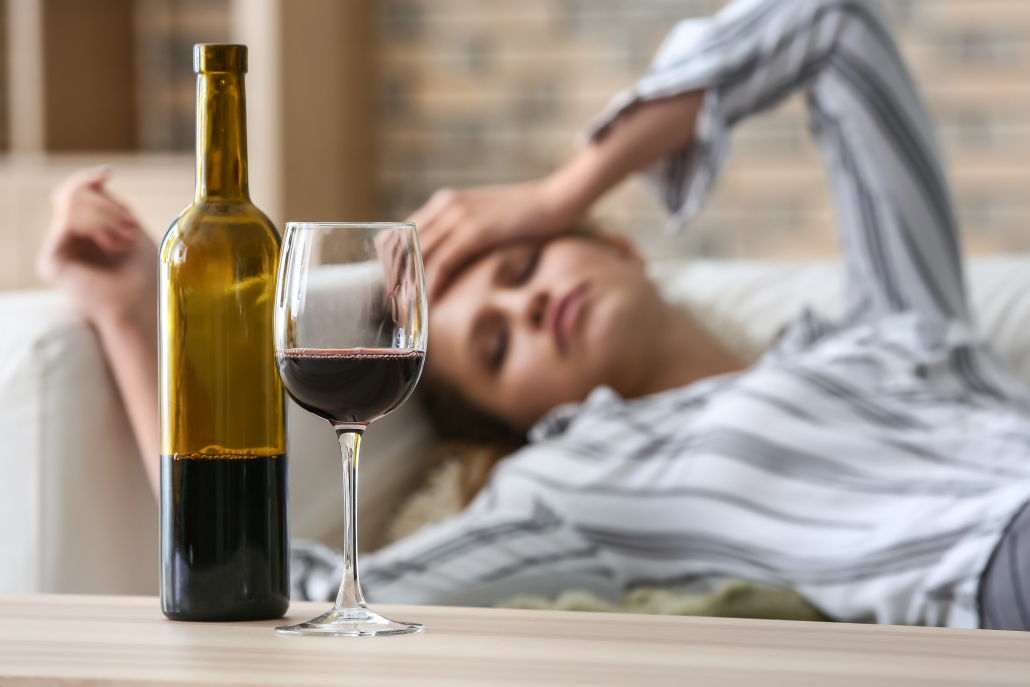 Glass and bottle of wine on table of drunk woman