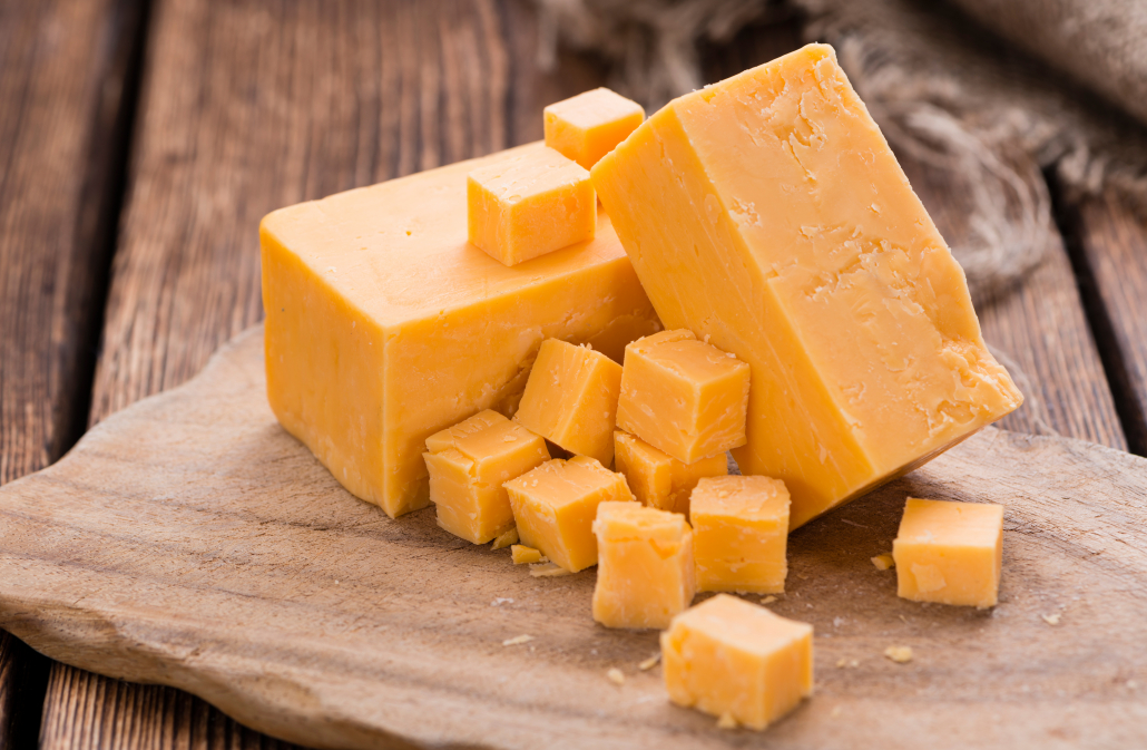 Portion of Cheddar (detailed close-up shot) on vintage wooden background