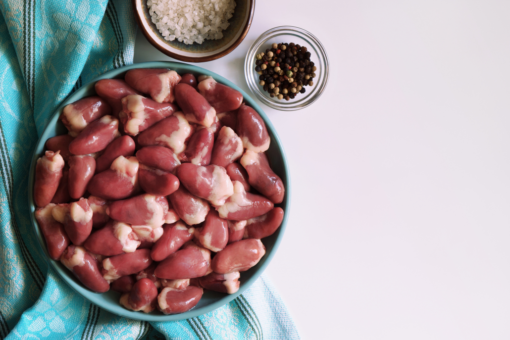 Raw chicken hearts, salt and pepper on white kitchen table. Organ meats are extremely rich in vitamins and minerals. Chicken hearts are an excellent source of CoQ10 – a very important nutrient responsible for proper cell and cardiac functioning.