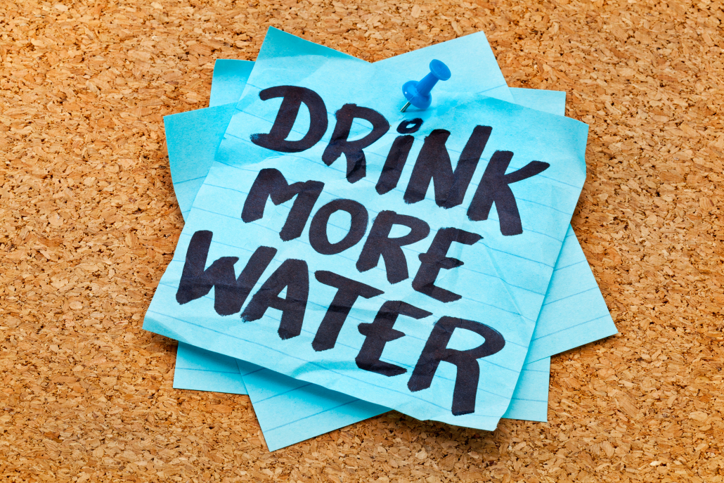 drink more water - hydration reminder - handwriting on blue sticky note posted on cork board