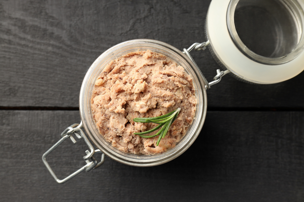 Glass jar of pate on wooden background
