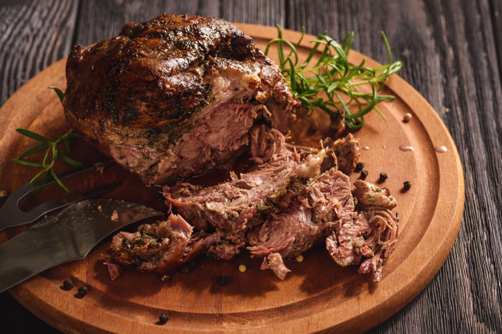 Roasted lamb fillet on wooden background.