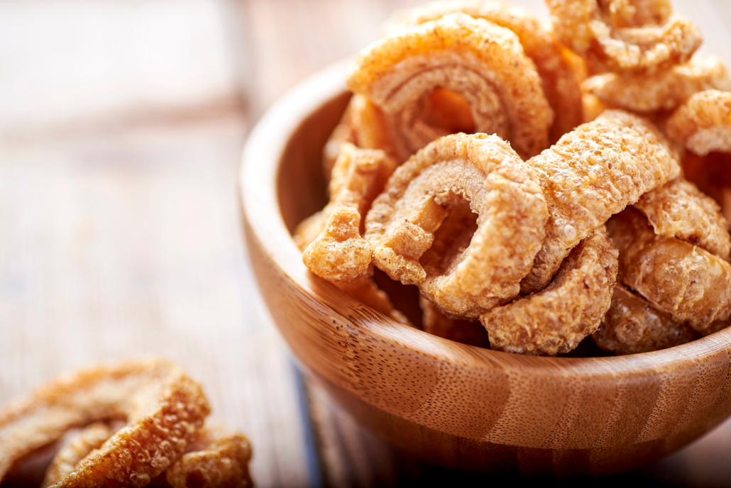 fried pork rinds, in a rustic container on a wooden background