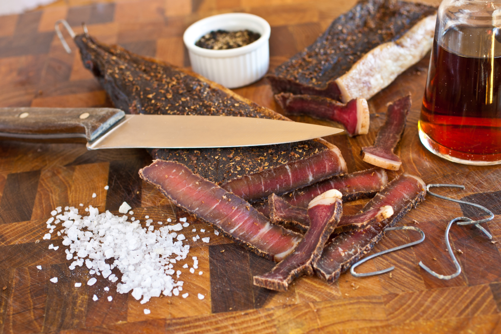 Biltong in South Africa as part of the country's culinary tradition, using good quality beef or game, coarse salt, ground spices and vinegar, and air dry the meat using wire hooks.