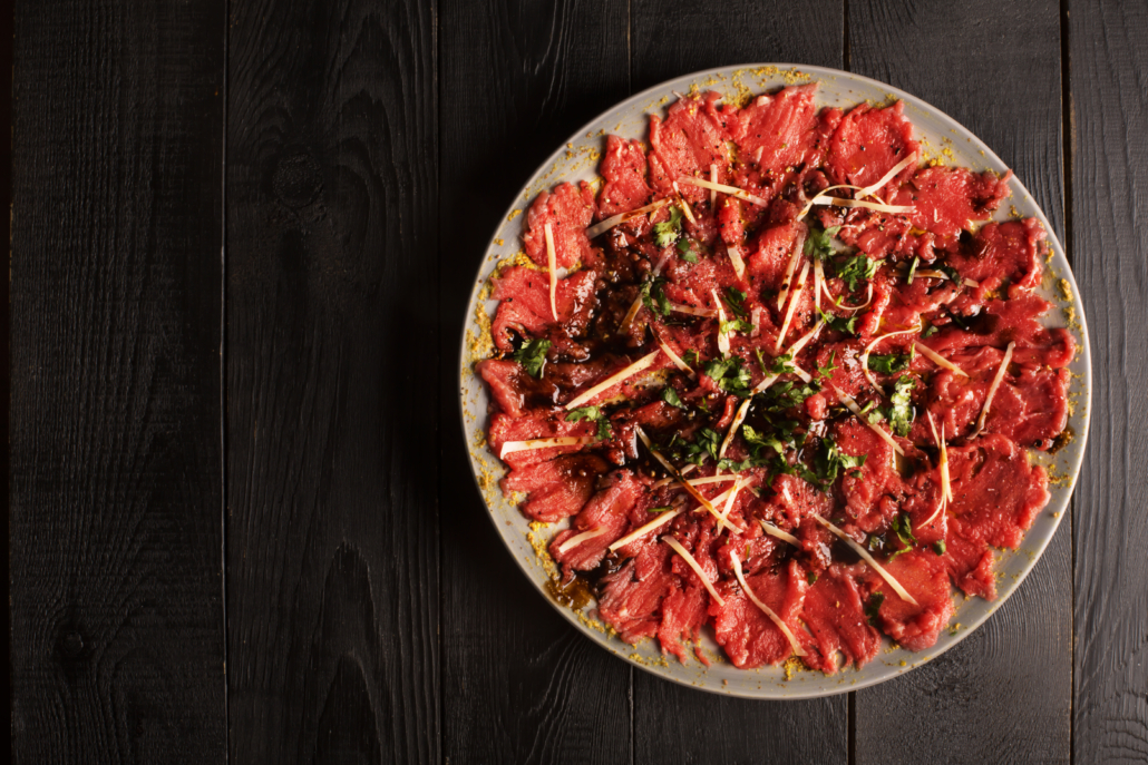 Carpaccio of beef on a plate with mustard and spices