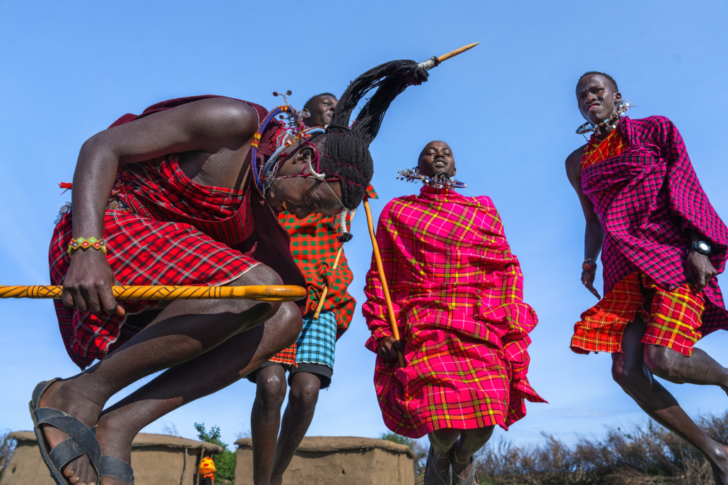 Maasai Mara man in traditional colorful clothing showing traditional Maasai jumping dance at Maasai Mara tribe village famous Safari travel destination near Maasai Mara National Reserve Kenya