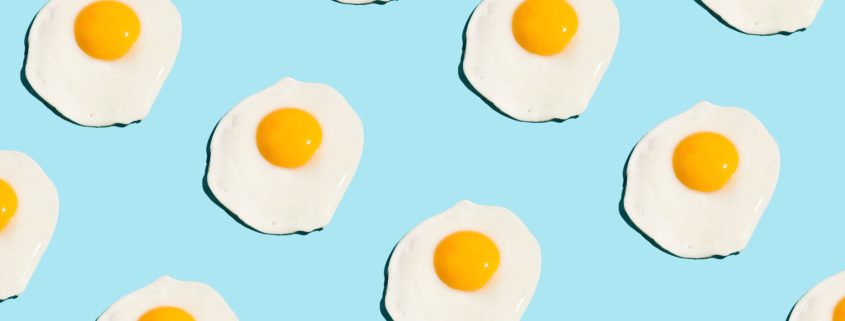 Fried eggs, scrambled eggs on blue background in food pattern. View from above. Food fashion minimalistic concept.