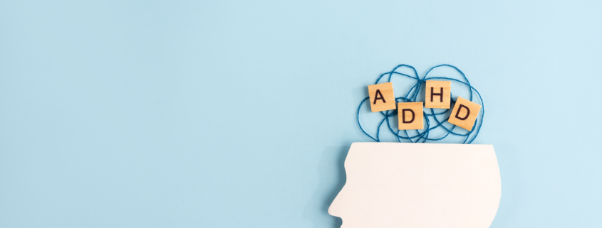 Silhouette of human head and wooden blocks with the letters ADHD on pastel background. Creative concept of attention deficit hyperactivity syndrome. Copy space