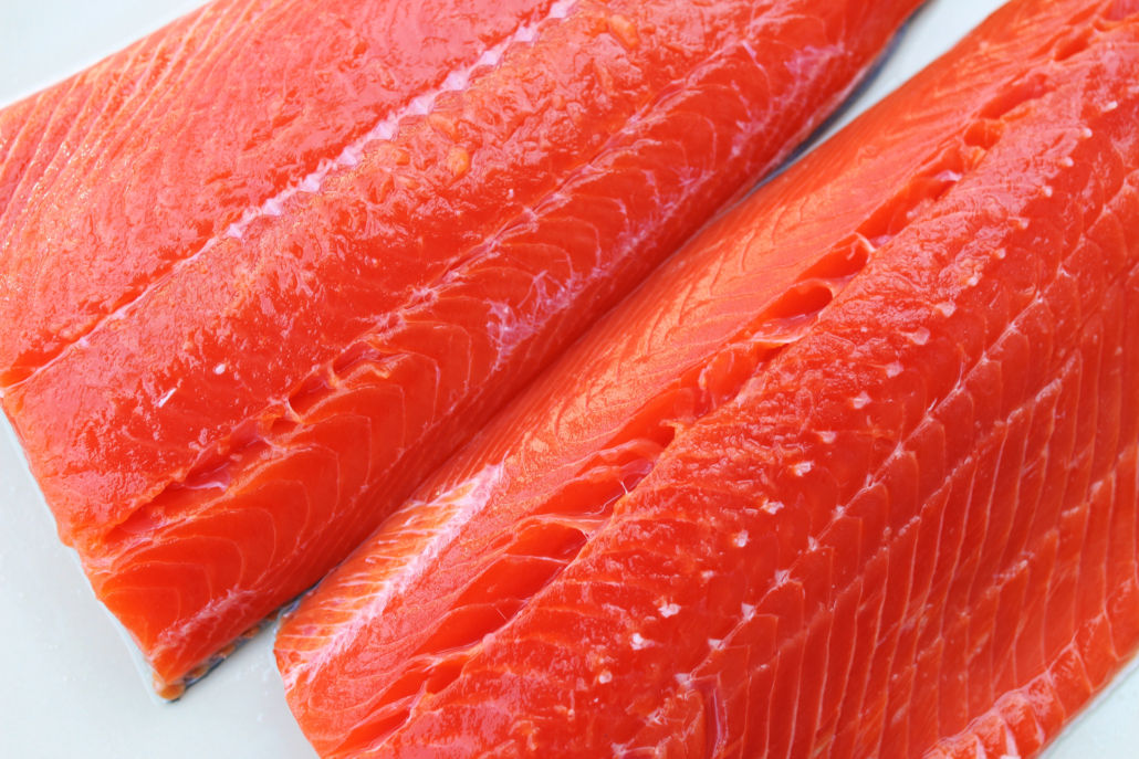Wild-caught sockeye salmon fillets on a white background.