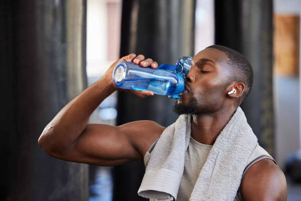Drinking water, fitness and gym with a black man athlete taking a break from his exercise or workout routine. Training, health and wellness with a sporty male having a drink for hydration or recovery.