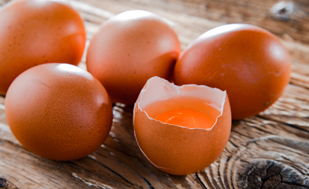 Composition with five chicken eggs on a wooden table.