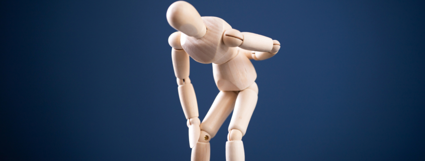 Wooden man with back pain. Medical concept.