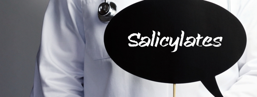 Salicylates. Doctor in smock holds up speech bubble. The term Salicylates is in the sign. Symbol of illness, health, medicine